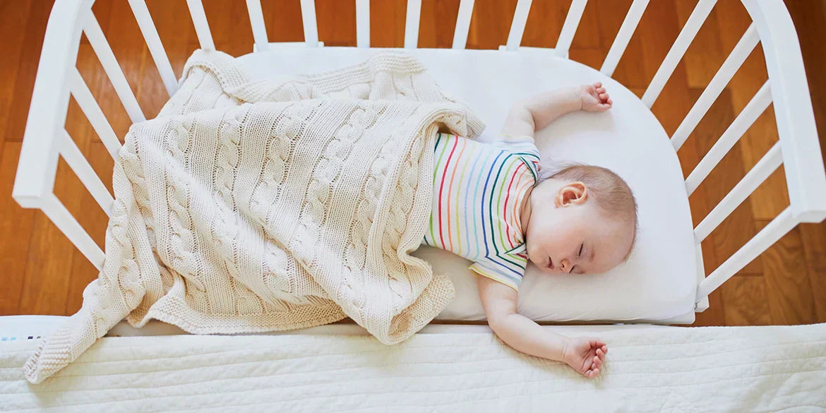 Baby schläft auf Beistellbabybett mit Wolldecke