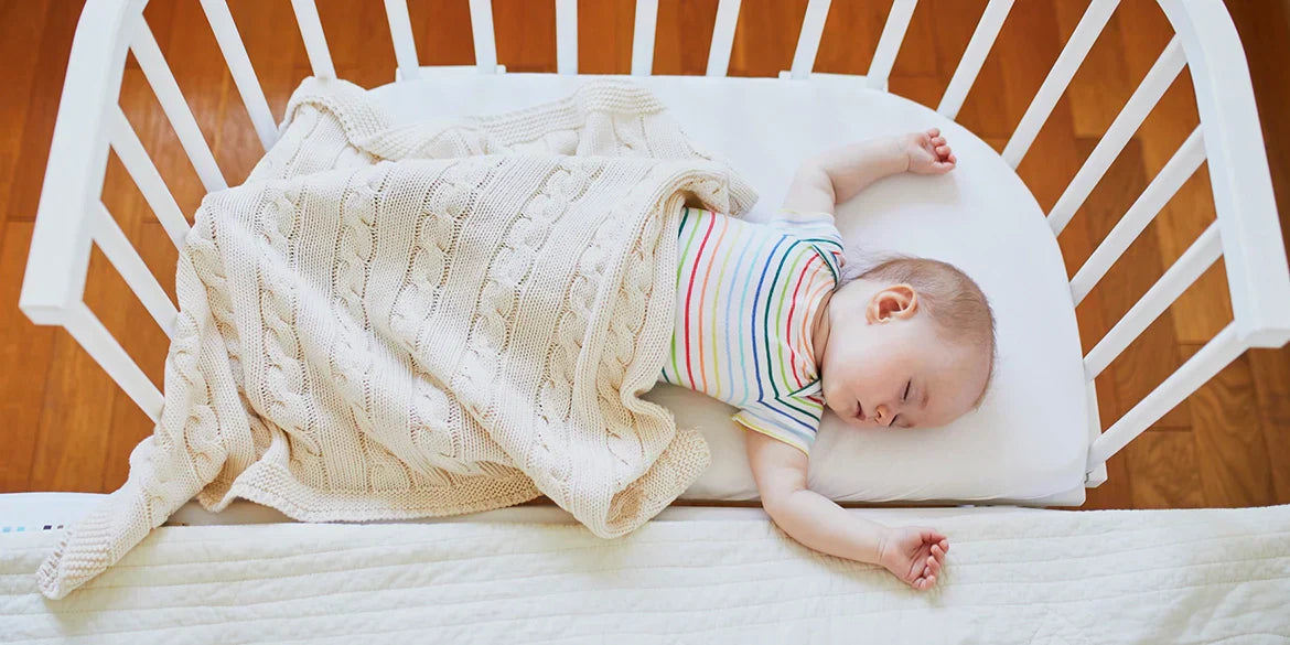 Baby schläft auf Beistellbabybett mit Wolldecke