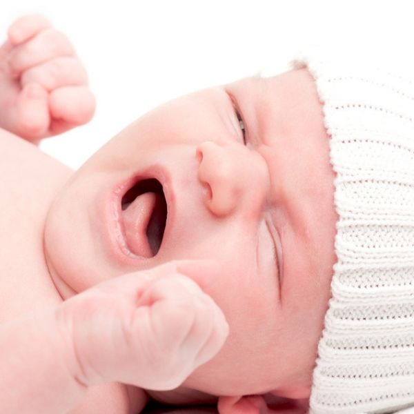 Baby mit weißer Mütze schreit
