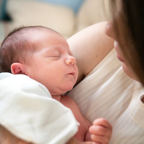 Mutter mit Baby Blues hält Neugeborenes im Arm