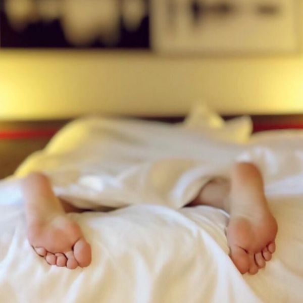 Frau liegt im Bett auf dem Bauch Füße gucken aus der Bettdecke heraus 