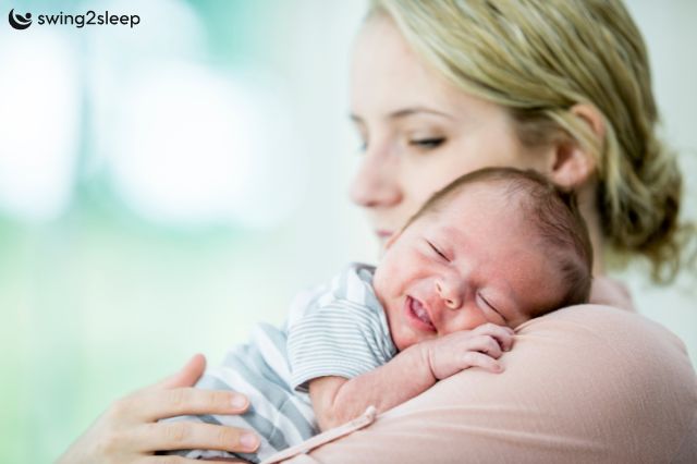 Rückenschmerzen vom Baby-Tragen: Mutter hält ihr Baby auf dem Arm