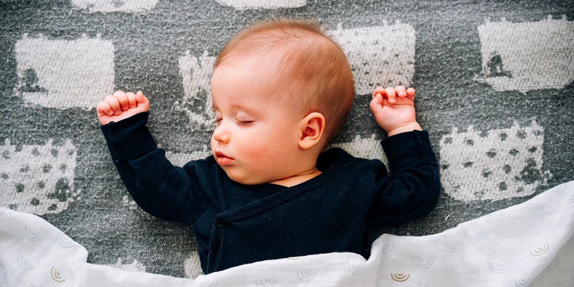 Baby schläft mit Händen neben dem Kopf