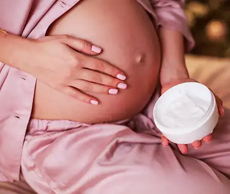 Schwangere Frau die ihren Bauch eincremt