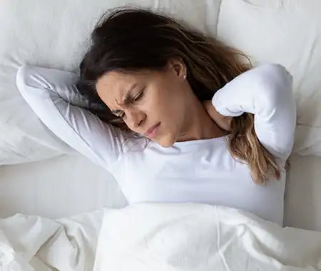 Frau mit Nackenschmerzen im Bett