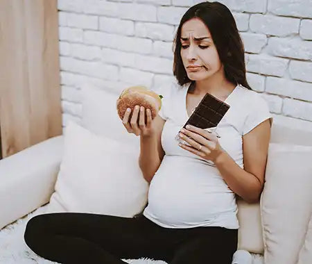 schwangere Frau mit Essen auf der Couch